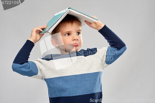 Image of little boy with roof of book on top of his head