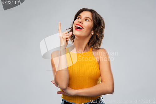 Image of happy smiling young woman pointing finger up