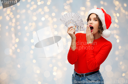 Image of surprised woman in santa hat with money