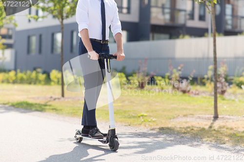 Image of young businessman riding electric scooter outdoors