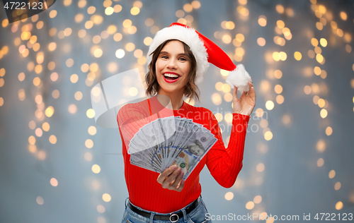 Image of happy woman in santa hat with money on christmas