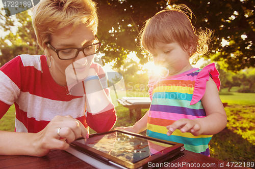 Image of mom and her little daughter using tablet computer