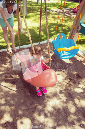 Image of mother and daughter swinging in the park