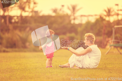 Image of mother and little daughter playing at backyard