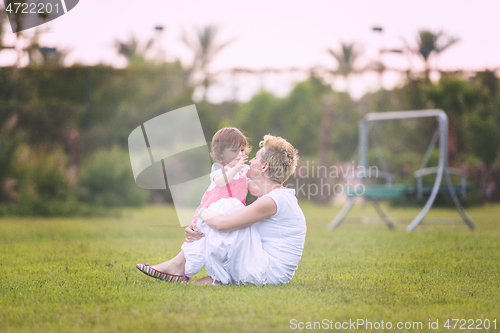 Image of mother and little daughter playing at backyard