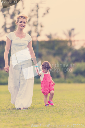 Image of mother and little daughter playing at backyard