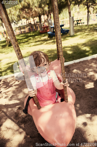 Image of little girl swinging  on a playground