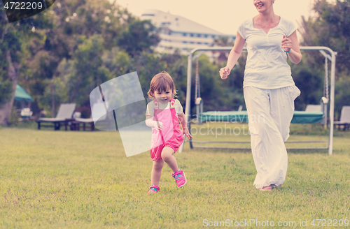 Image of mother and little daughter playing at backyard