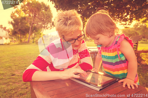 Image of mom and her little daughter using tablet computer