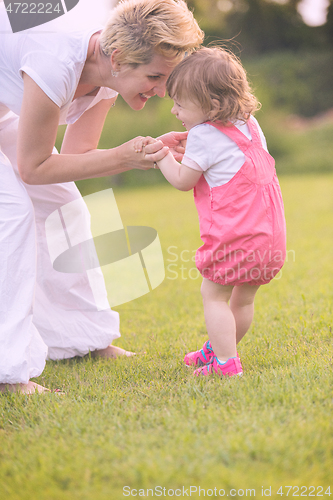 Image of mother and little daughter playing at backyard