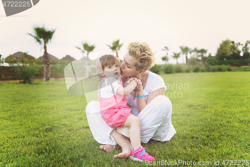 Image of mother and little daughter playing at backyard