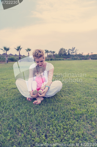 Image of mother and little daughter playing at backyard