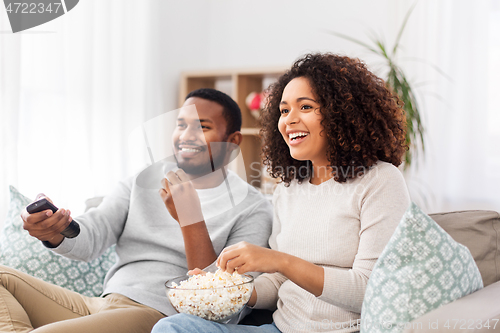 Image of african couple with popcorn watching tv at home