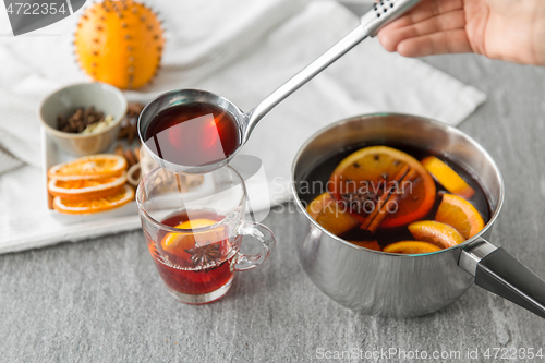 Image of hand with ladle pouring hot mulled wine to glass