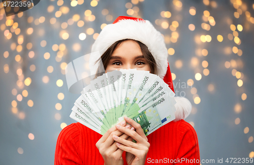 Image of happy woman in santa hat with money on christmas