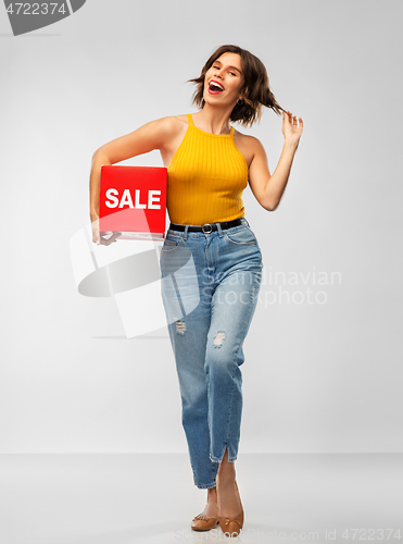 Image of happy smiling young woman posing with sale sign