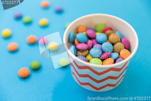 Image of candy drops in paper cup on blue background