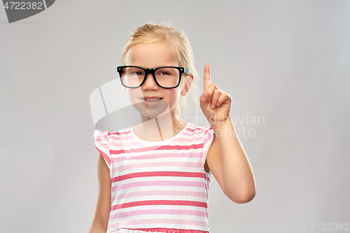 Image of smiling little girl in glasses pointing finger up