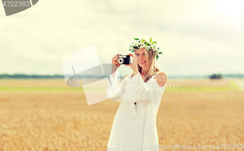 Image of happy woman with film camera in wreath of flowers