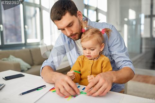 Image of working father with baby daughter at home office