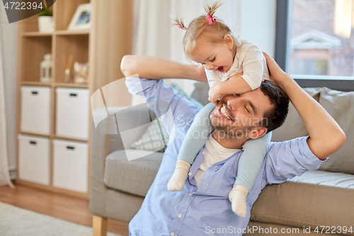 Image of father riding little baby daughter on neck at home