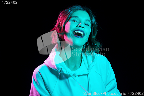 Image of woman wearing hoodie in neon lights over black