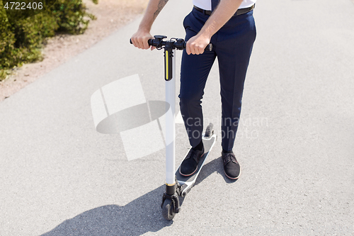 Image of young businessman riding electric scooter outdoors