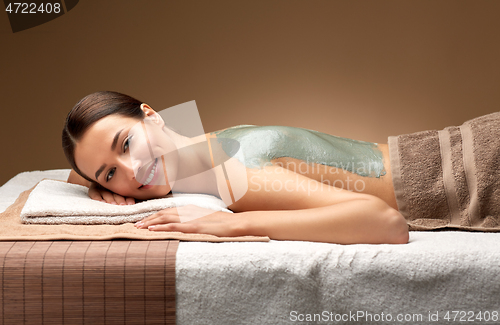 Image of woman with blue clay mask on back in spa
