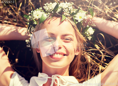 Image of happy woman in wreath of flowers lying on straw