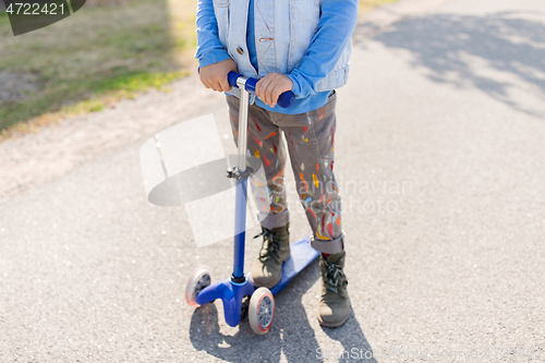 Image of close up of little boy with scooter on road