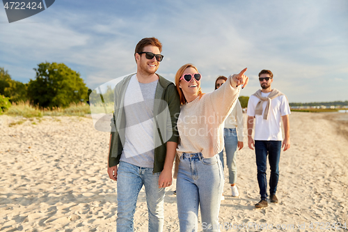 Image of happy friends walking along summer beach