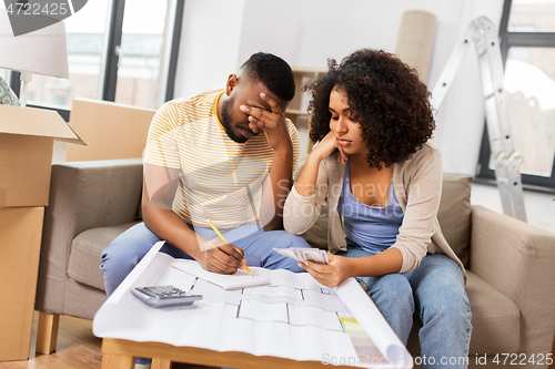 Image of sad couple with blueprint counting money at home
