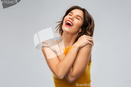 Image of happy grateful young woman in mustard yellow top