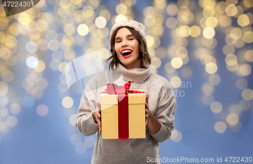 Image of young woman in winter hat holding christmas gift