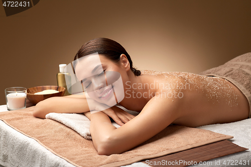 Image of woman lying with sea salt scrub on skin at spa