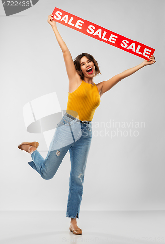 Image of happy smiling young woman posing with sale banner