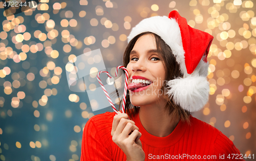 Image of woman in santa hat licks candy canes on christmas