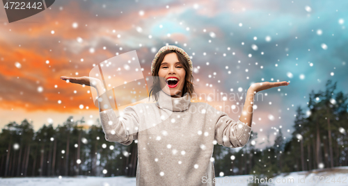 Image of woman in hat and sweater over winter forest