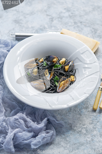 Image of Black seafood spaghetti pasta with mussels over stone background. Mediterranean delicious food