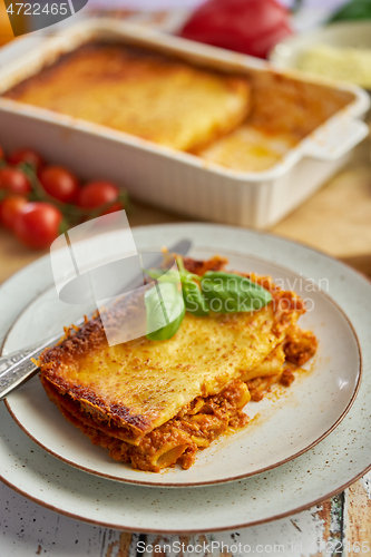 Image of Homemade tasty meat lasagna with fresh basil and parmesan cheese in a plate on wooden background