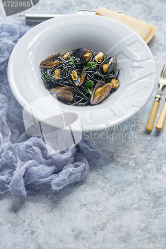 Image of Black seafood spaghetti pasta with mussels over stone background. Mediterranean delicious food