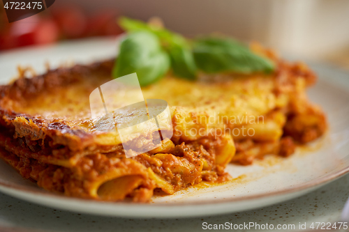 Image of Homemade tasty meat lasagna with fresh basil and parmesan cheese in a plate on wooden background