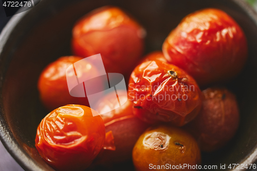 Image of Roasted cherry Tomatoes placed in a ceramic dark bowl. Close up macro shot.