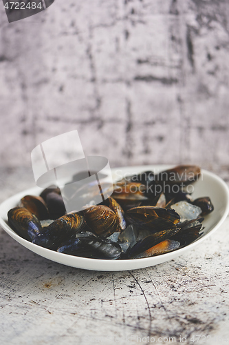 Image of Fresh and raw sea mussels in white ceramic bowl on stone background