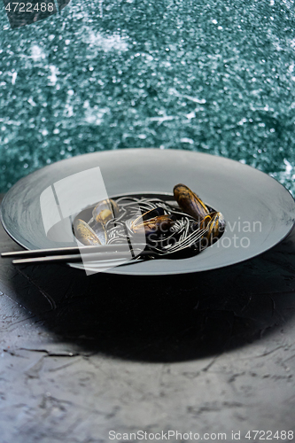 Image of Seafood black spaghetti pasta with clams served on black plate on dark stone