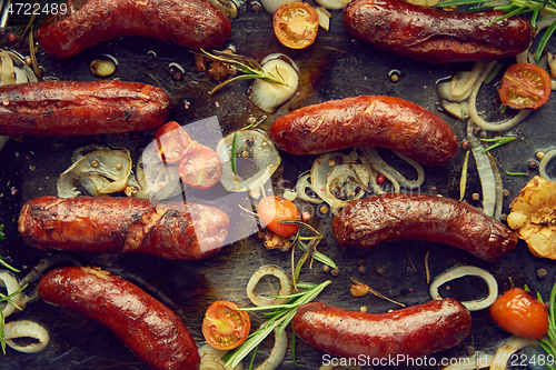 Image of Top view on delicious grilled sausages served with onion, tomatoes, garlic, bread and herbs