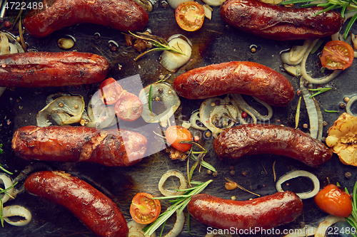 Image of Top view on delicious grilled sausages served with onion, tomatoes, garlic, bread and herbs