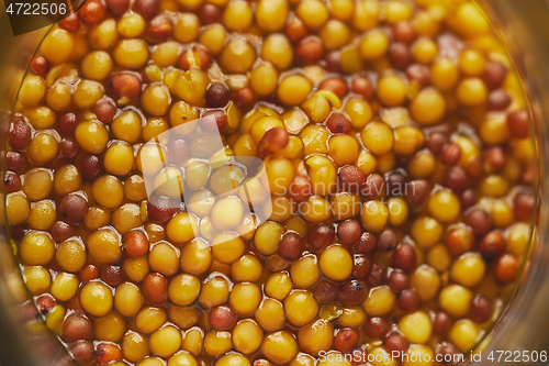 Image of French mustard with whole seeds served in glass jar. Selective focus