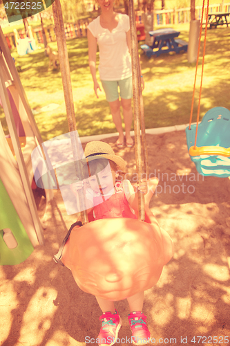 Image of mother and daughter swinging in the park