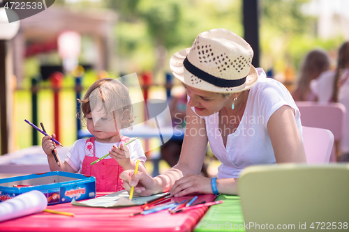 Image of mom and little daughter drawing a colorful pictures